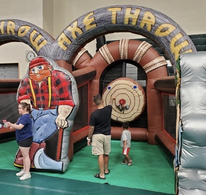 Customers playing inflatable axe throwing game at a Backyard Party Rentals event