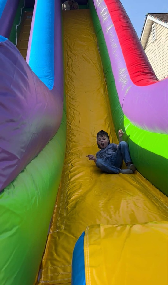 Kid riding the 22' Dual Wacky Dry Slide at a Backyard Party Rentals event in St. Charles County MO