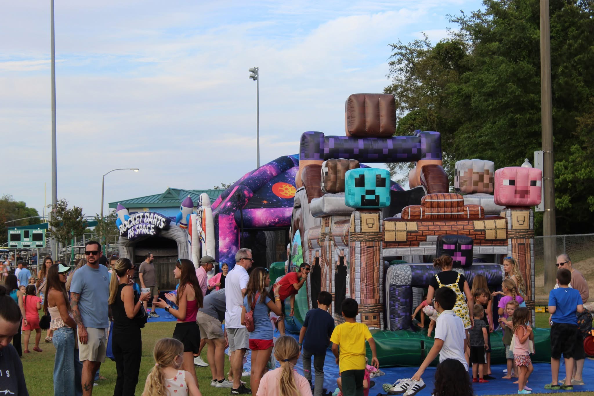Large event with multiple inflatable bounce houses and obstacle courses set up by Jumptastic Inflatables