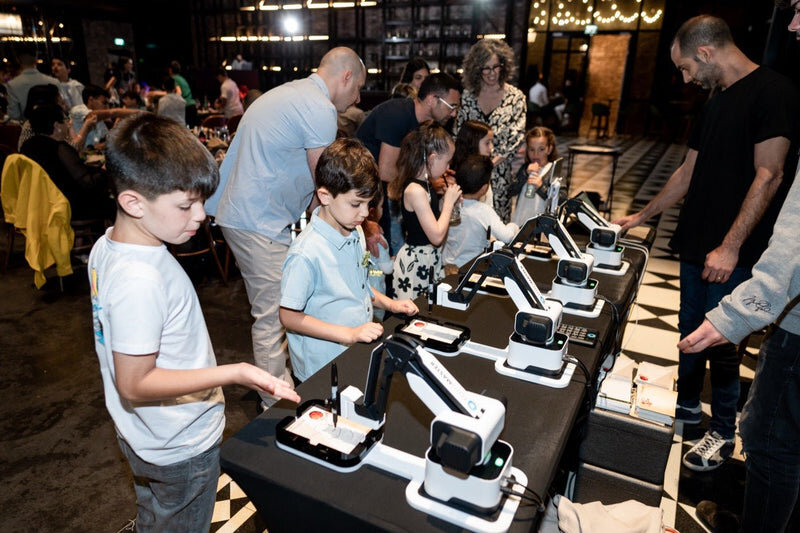 Kids gathered around the AI robot caricature artist at a birthday party