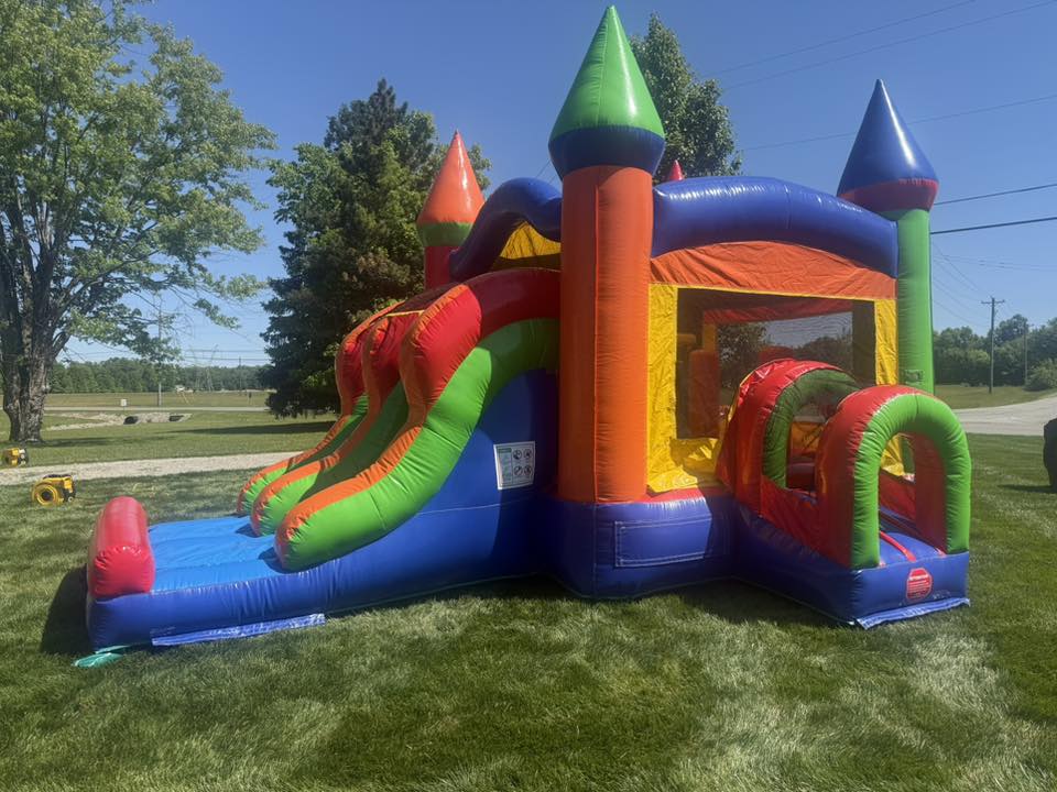 Classic Castle Combo rainbow bounce house with double lane slide set up in a yard